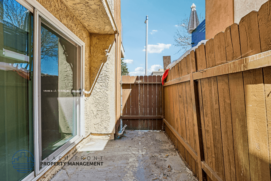 A wooden fence is in front of a tan building.